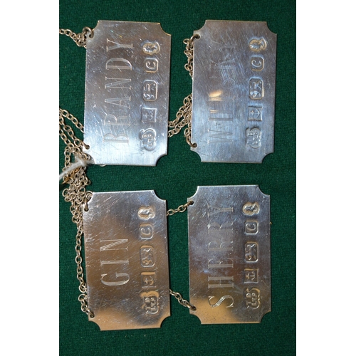 1013 - A set of four silver decanter labels.