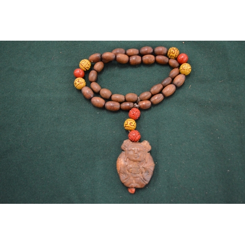 1101 - A wooden bead necklace with a pendant carved as a Buddha.