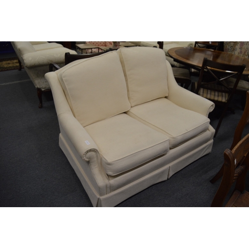 276 - A small cream upholstered two seater settee.