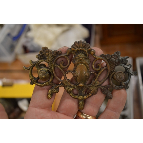 715 - A collection of ornate brass furniture handles and escutcheons.