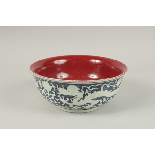 141 - A CHINESE BLUE AND WHITE DRAGON BOWL, with copper red interior. 26.5cms diameter.