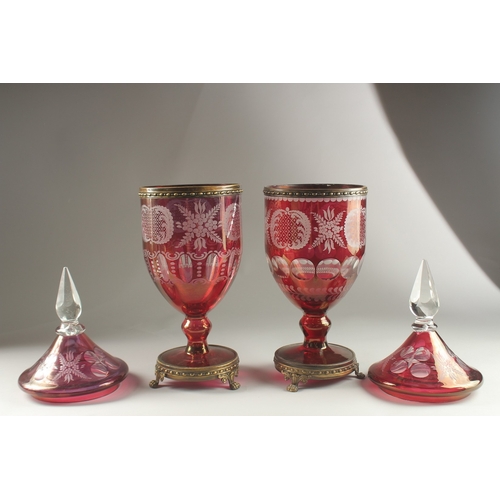 49 - A LARGE PAIR OF BOHEMIAN RUBY TINTED URNS AND COVERS on metal bases with claw feet. 54cms high, one ... 