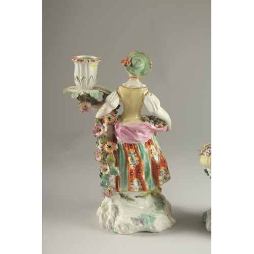 61 - A PAIR OF DERBY FIGURE CANDLESTICKS, as a woman and man, encrusted with flowers, each with a candle ... 