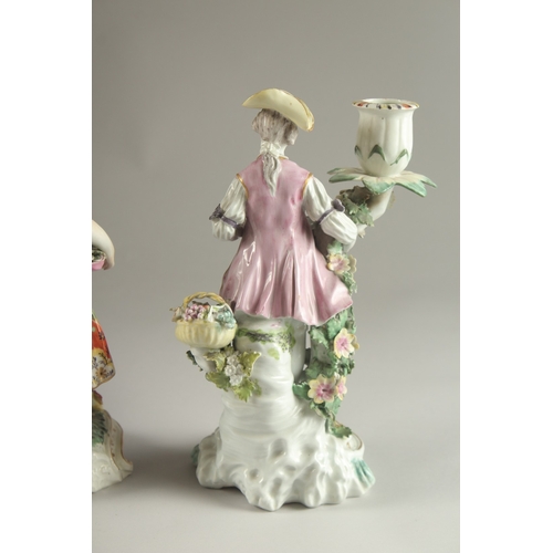 61 - A PAIR OF DERBY FIGURE CANDLESTICKS, as a woman and man, encrusted with flowers, each with a candle ... 