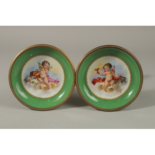 71 - A GOOD PAIR OF SEVRES APPLE GREEN PORCELAIN CIRCULAR TAZZAS painted with cupids, the ormolu bases wi... 