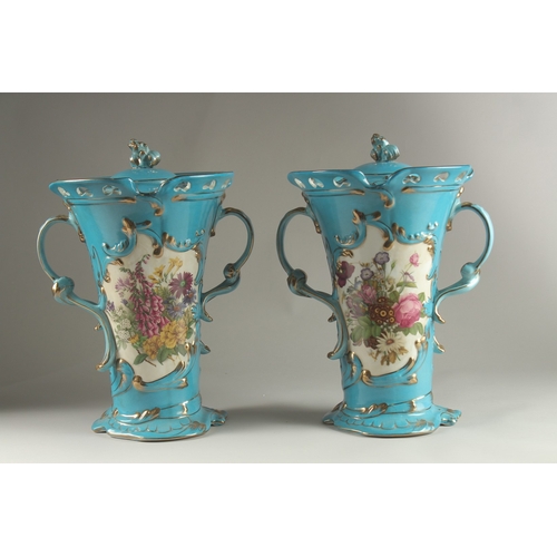 81 - A PAIR OF SEVRES DESIGN BLUE GROUND, TWO HANDLED VASES with reverse panels of flowers. 33cms high.... 