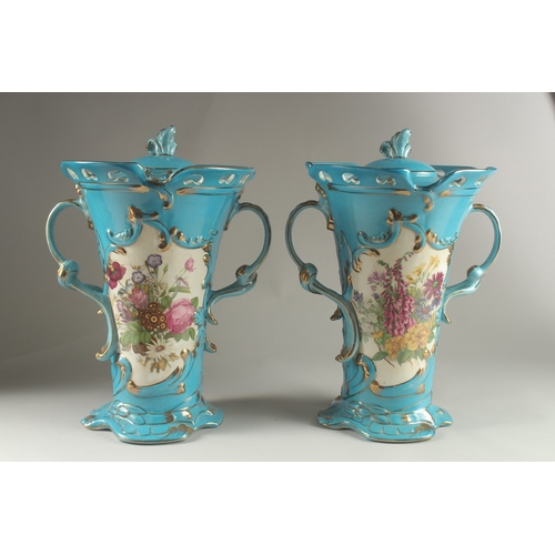 81 - A PAIR OF SEVRES DESIGN BLUE GROUND, TWO HANDLED VASES with reverse panels of flowers. 33cms high.... 