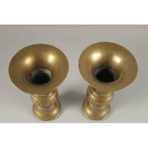 1008 - A PAIR OF CHINESE BRASS TRUMPET FORM VASES, with archaic style designs, the bases with indistinct ma... 