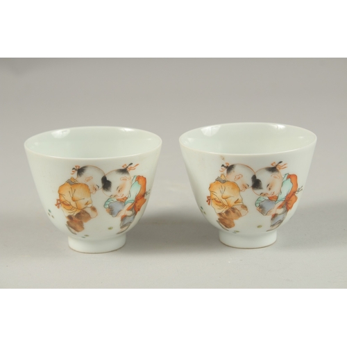 1019 - A PAIR OF CHINESE POLYCHROME PORCELAIN TEA CUPS, painted with boys playing, the base with red charac... 