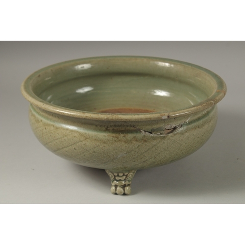 1043 - A 16TH CENTURY GREEN GLAZED DEEP CIRCULAR BOWL, raised on three lion feet. 15cm high, 32cm wide.