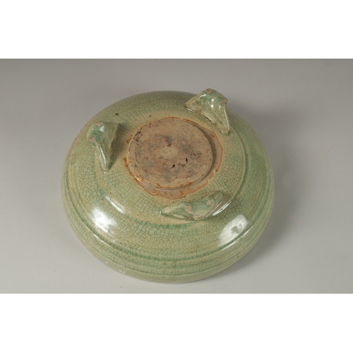 1044 - A 16TH CENTURY GREEN GLAZED DEEP CIRCULAR BOWL, raised on three lion feet. 13cm high, 30cm wide.