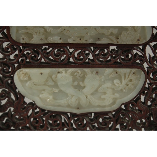 1045 - A PAIR OF SHAPED JADE PLAQUES INSET WITHIN A HARDWOOD FRAME, creating a carved wood table screen, he... 