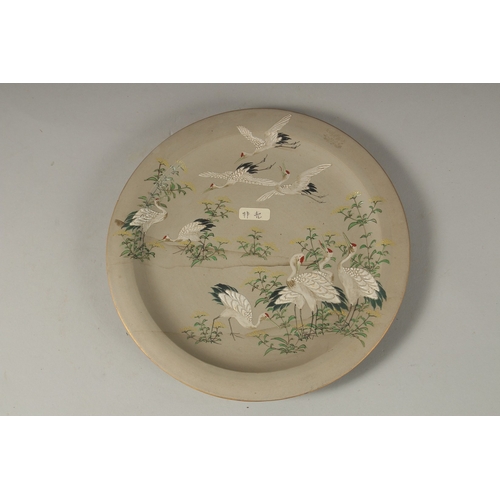 1065 - A JAPANESE ENAMELLED POTTERY DISH, depicting cranes and flora, the base with carved signature, 19cm ... 