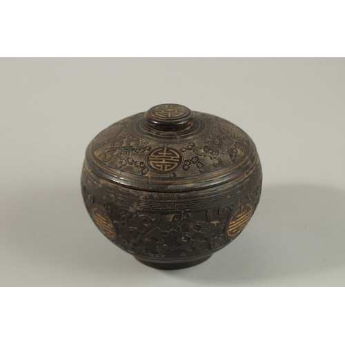 1071 - A CHINESE CARVED COCONUT LIDDED BOX, carved with longevity symbols and precious objects, 11.5cm diam... 