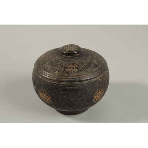 1071 - A CHINESE CARVED COCONUT LIDDED BOX, carved with longevity symbols and precious objects, 11.5cm diam... 