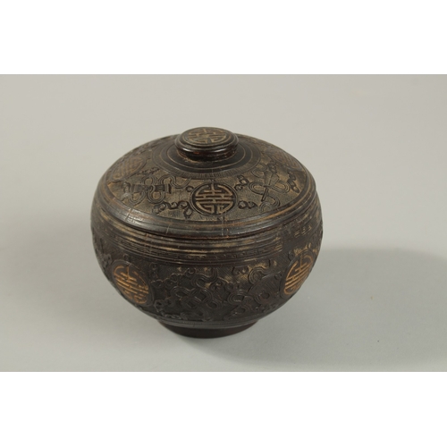 1071 - A CHINESE CARVED COCONUT LIDDED BOX, carved with longevity symbols and precious objects, 11.5cm diam... 