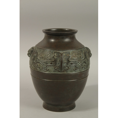 1216 - A CHINESE BRONZE TWIN HANDLE VASE, with relief band of archaic decoration, 23cm high.