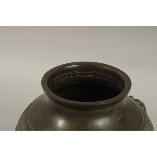 1216 - A CHINESE BRONZE TWIN HANDLE VASE, with relief band of archaic decoration, 23cm high.