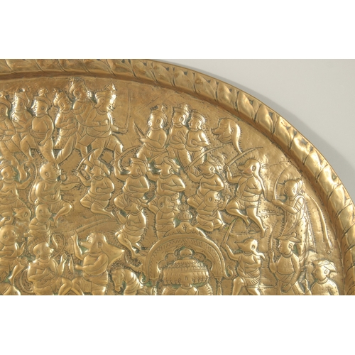 137 - A LARGE 19TH CENTURY NORTH INDIAN EMBOSSED BRASS TRAY, depicting a battle scene from the Ramayana wi... 