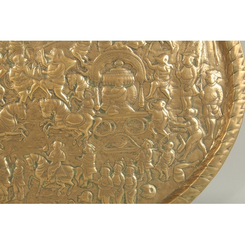 137 - A LARGE 19TH CENTURY NORTH INDIAN EMBOSSED BRASS TRAY, depicting a battle scene from the Ramayana wi... 