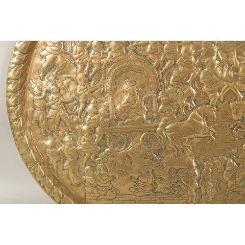 137 - A LARGE 19TH CENTURY NORTH INDIAN EMBOSSED BRASS TRAY, depicting a battle scene from the Ramayana wi... 