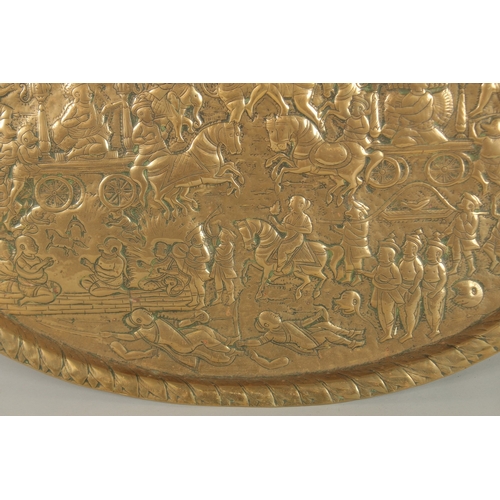 137 - A LARGE 19TH CENTURY NORTH INDIAN EMBOSSED BRASS TRAY, depicting a battle scene from the Ramayana wi... 