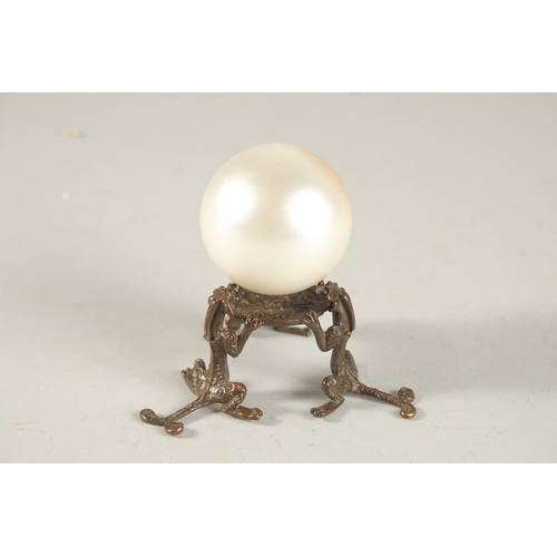 209 - A PEARLESCENT SPHERICAL ORNAMENT ON A BRONZE STAND, the stand formed with tripod chilong legs.