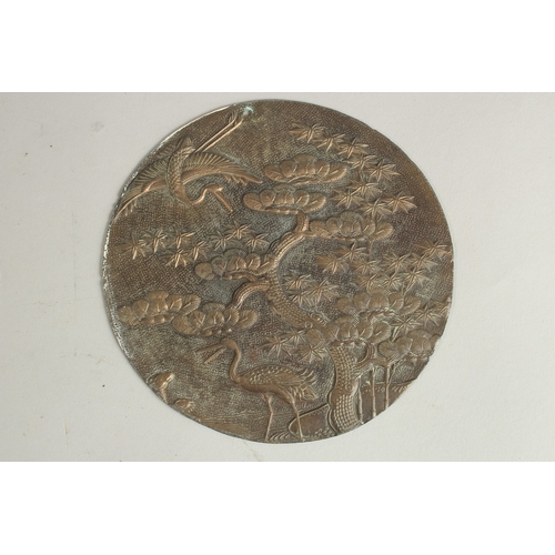 214 - AN ENGRAVED AND CHASED METAL CIRCULAR PLAQUE, depicting cranes beside a tree, 13.5cm diameter.