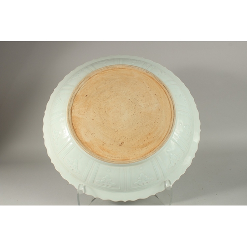 301 - A LARGE CHINESE CELADON GLAZE CARVED DRAGON CHARGER, with petal-form rim, 44cm wide.