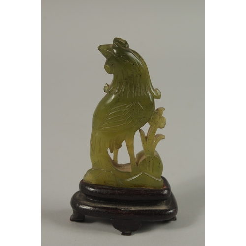 37 - A SMALL CHINESE CARVED JADE COCKEREL AND WOODEN STAND, jade 8.5cm high.