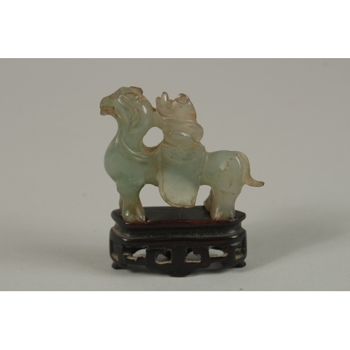 38 - A CHINESE CARVED JADE MINIATURE FIGURE OF A MUSICIAN ON HORSEBACK, with wooden stand, jade 5cm long.