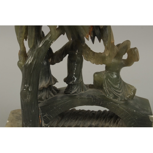 41 - A LARGE CHINESE CARVED JADE GROUP, depicting three figures on a bridge beneath a tree, together with... 