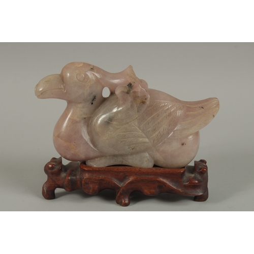 42 - A LARGE CHINESE CARVED ROSE QUARTZ FIGURE OF A BIRD, on a carved hardwood stand, quartz 20cm long.