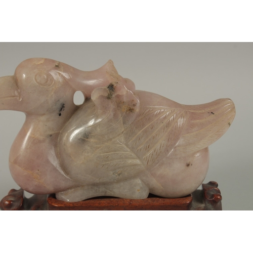 42 - A LARGE CHINESE CARVED ROSE QUARTZ FIGURE OF A BIRD, on a carved hardwood stand, quartz 20cm long.