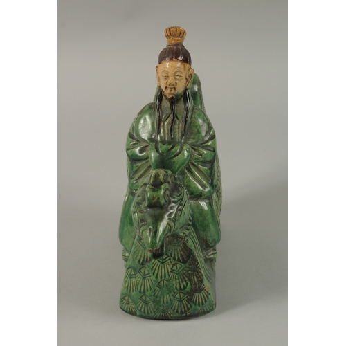 51 - A CHINESE GREEN AND YELLOW GLAZED POTTERY FIGURE of a man on a mythical bird, 22cm high.