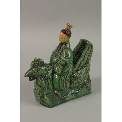 51 - A CHINESE GREEN AND YELLOW GLAZED POTTERY FIGURE of a man on a mythical bird, 22cm high.