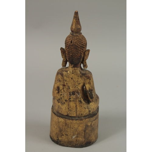 55 - A GILDED CARVED WOOD BUDDHA, with inscriptions to base, 25cm high.