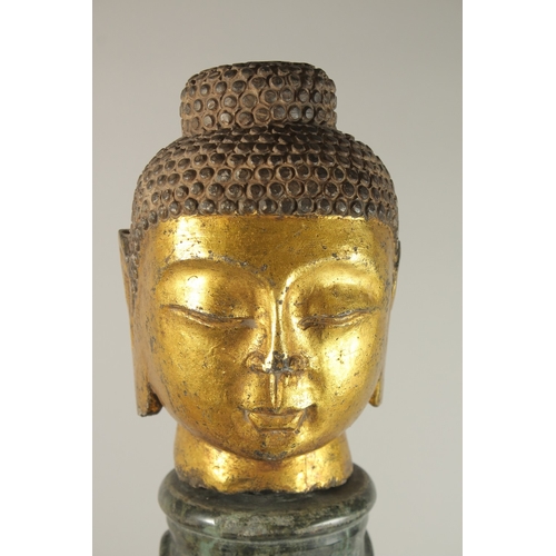 58 - A GILDED STONE BUDDHA HEAD, standing on a spiraled marble column (with inset metal rod to support th... 