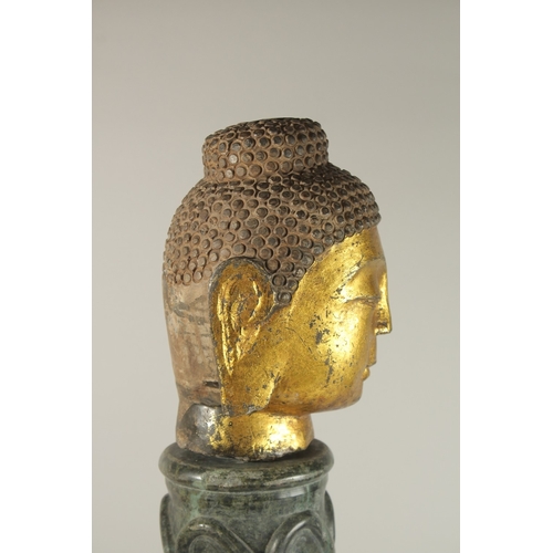 58 - A GILDED STONE BUDDHA HEAD, standing on a spiraled marble column (with inset metal rod to support th... 