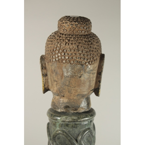 58 - A GILDED STONE BUDDHA HEAD, standing on a spiraled marble column (with inset metal rod to support th... 