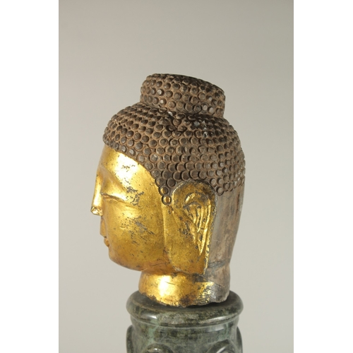 58 - A GILDED STONE BUDDHA HEAD, standing on a spiraled marble column (with inset metal rod to support th... 