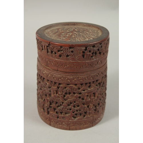 61 - A CHINESE FINELY CARVED BAMBOO LIDDED BRUSH POT, with a continuous village scene, 15cm high.