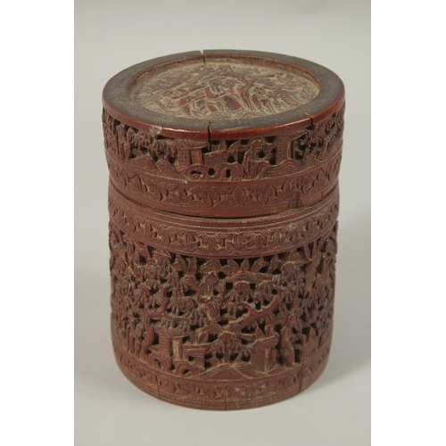 61 - A CHINESE FINELY CARVED BAMBOO LIDDED BRUSH POT, with a continuous village scene, 15cm high.