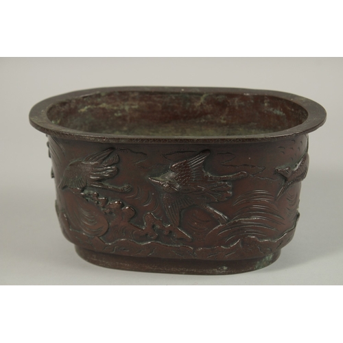 65 - A BRONZE OVAL FORM JARDINIERE, with relief decoration of cranes, the base with character mark, 22cm ... 