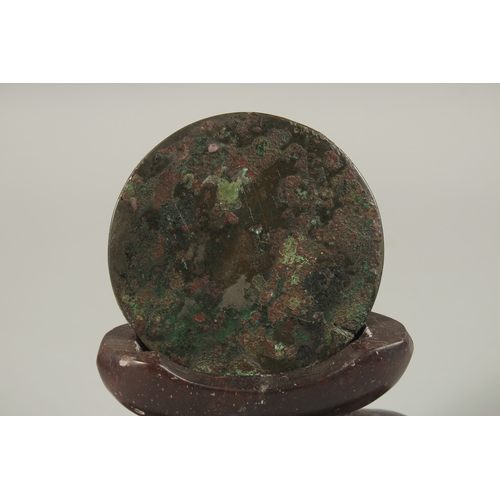 67 - A CHINESE CIRCULAR BRONZE MIRROR, with carved soapstone stand, mirror 9cm diameter.