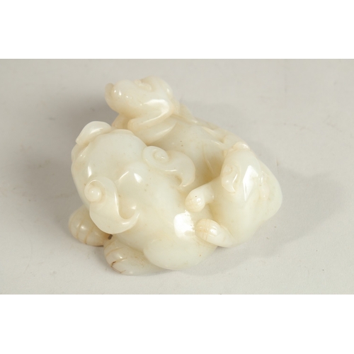 95 - A CHINESE WHITE JADE CARVING OF A MYTHICAL LION, with incised characters to base, 11cm wide, 5cm hig... 