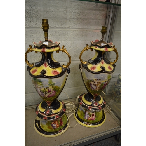 614 - A large pair of decorative pottery twin handled lamps with circular bases.