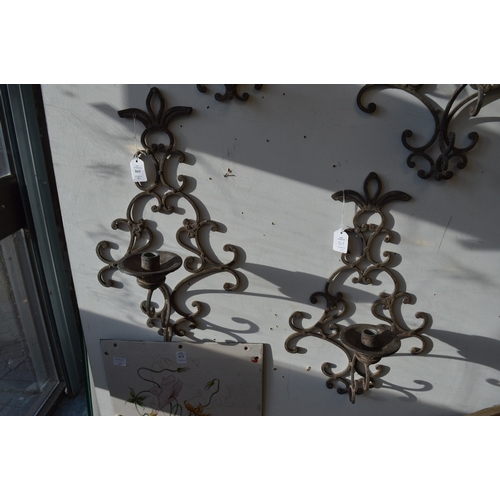 869 - A pair of wrought iron wall mounted candle holders.