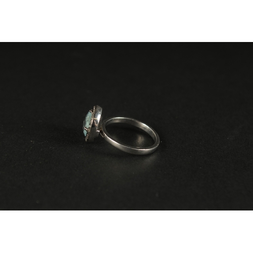 1020 - A RING SET WITH AN OVAL CHECKERBOARD CUT AQUAMARINE AND A HALO OF DIAMOND in silver. Aquamarine 1.05... 