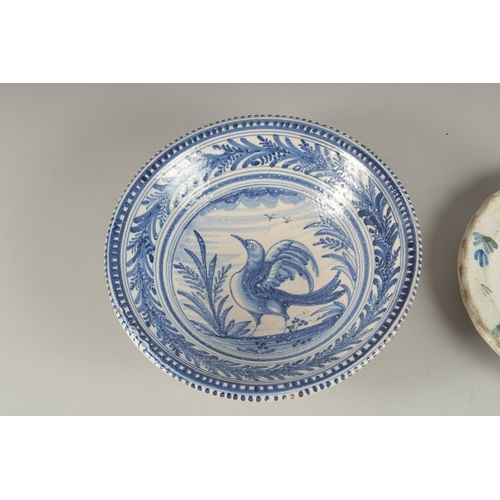 592 - A CONTINENTAL BLUE AND WHITE FAIENCE POTTERY BOWL, decorated with a bird, and a faience dish decorat... 